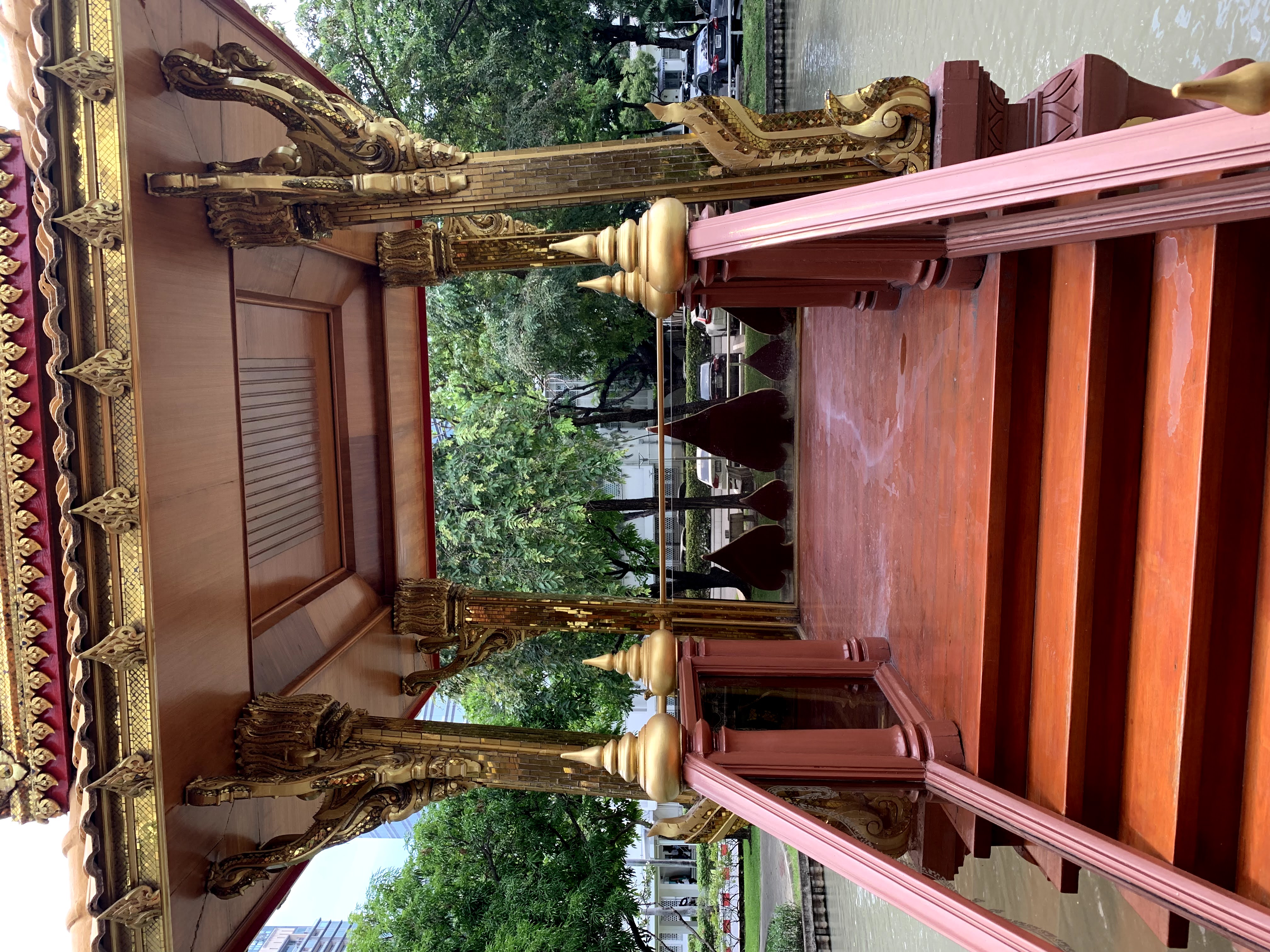 Color photograph, view up several low steps into the red and gold gazebo, noting the gilded supports or pillars and gilded cornice