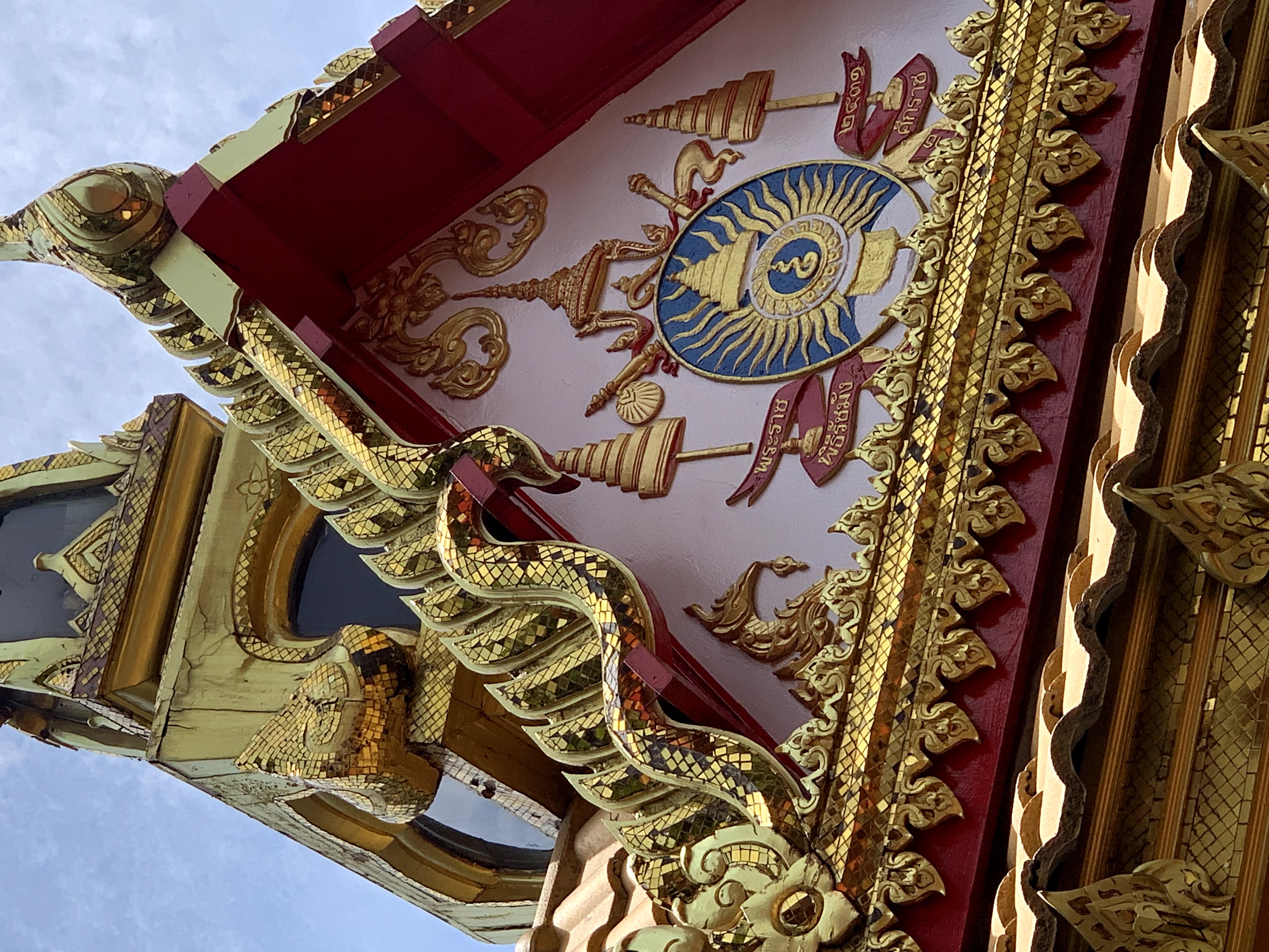 Color photograph, detail view of gazebo gable with painted wood, gilded wood, and a crest