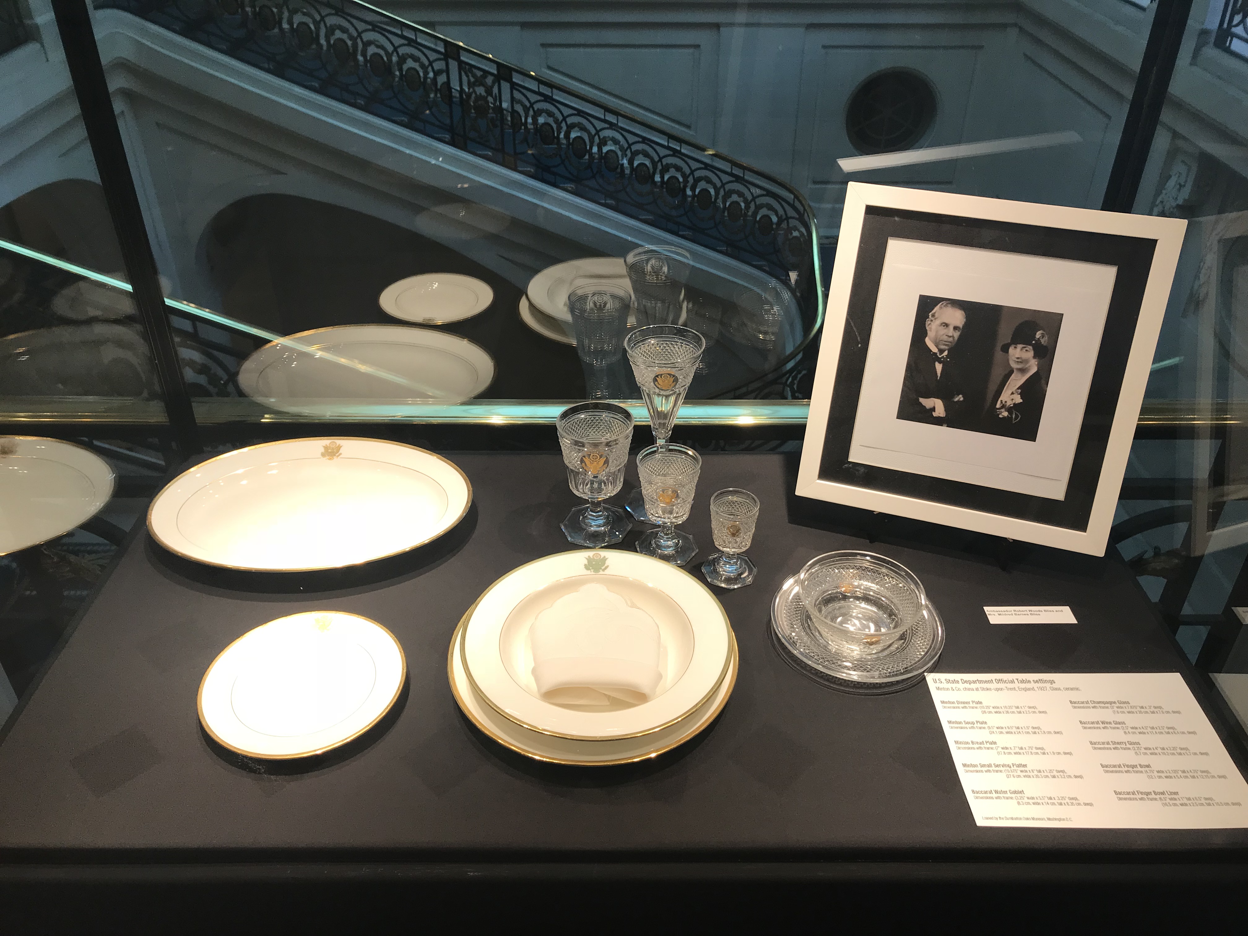 Color photograph, museum display case with crystal glassware, finger bowl, and china, and a photograph