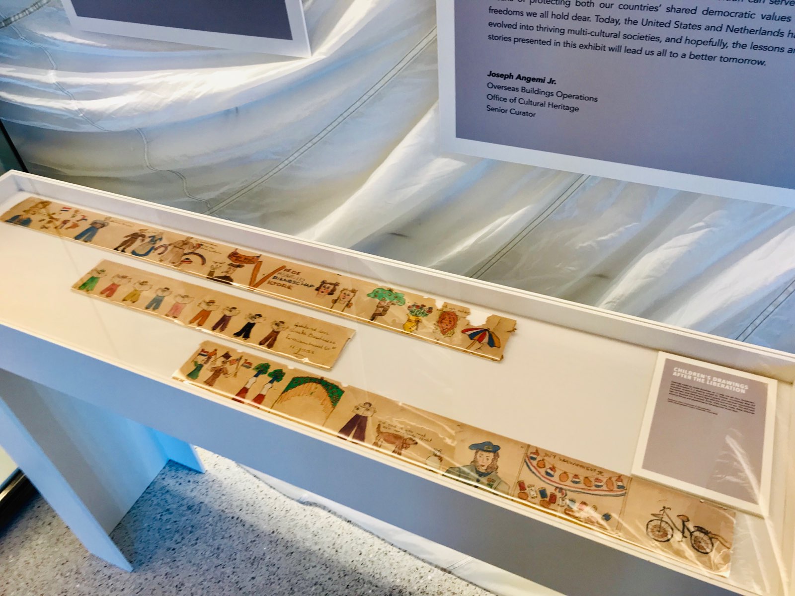 Color photograph, museum display case with sketches on three long, narrow boards.