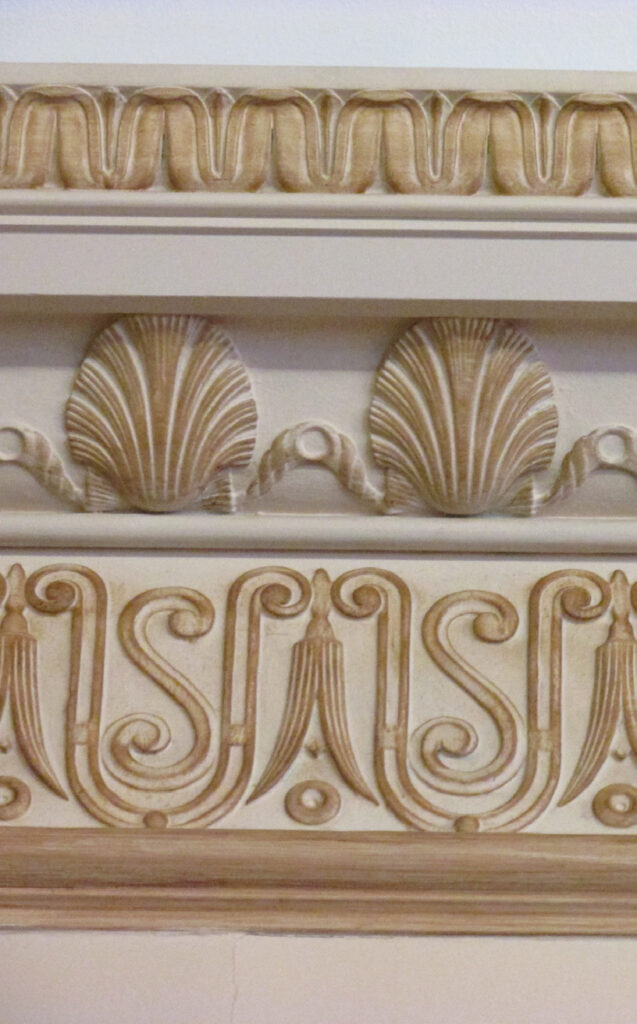 Color photograph, detail view showing a painted cornice and frieze with the letters “USA”.
