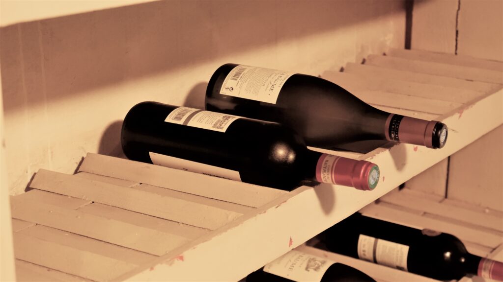 Color photograph, detail view of a wine cellar to show bottles stored on shelves