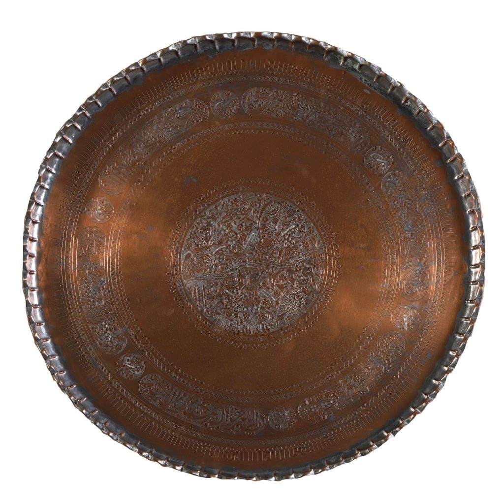 Tinned copper, circa 19th century

U.S. Embassy Damascus, Syria

This antique tinned copper tray displays exceptional repoussé (hammered relief) work. Originating from the Middle East, the tray features a central circular design with stylized figures and animals in a hunting scene. It exhibits traditional metalworking techniques with intricate geometric patterns surrounding the central scene. The “pie crust” style scalloped rim adds to the piece’s appeal and is a testament to the cultural exchange and artistry of the region.

Until 2012, this tray was displayed at U.S. Embassy Damascus until U.S. personnel were evacuated and the embassy was closed during the rapidly deteriorating security situation in the Syrian capital. Today it is displayed in the State Department’s Office of Cultural Heritage as a reminder of the importance during times of war and upheaval in host countries to protect and preserve art and artifacts which chronicle our nation’s cultural and diplomatic history abroad.
