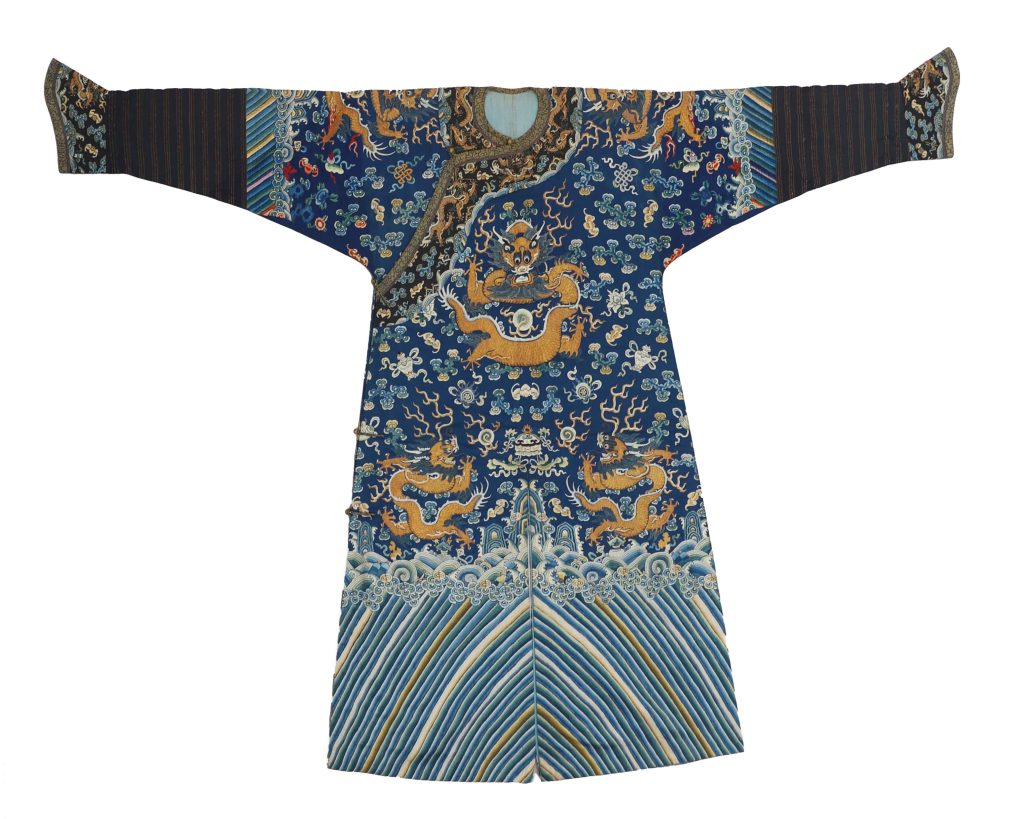 Embroidered silk, circa 1875

U.S. Consulate General, Hong & Kong & Macau

At first glance, a Chinese imperial dragon robe looks just as it is named – a robe adorned with dragon designs. But there was a complex system dictating each robe’s colors, designs, and features that would be indecipherable without an instruction manual. The Qing dynasty, in particular, took the dragon robe to a level of complexity unrivalled in the history of China.

In the imperial court of the Qing dynasty (1639- 1913), the right to wear a dragon robe and its accessories was conferred by rank and entitlement. Robes prominently featured an intricately embroidered dragon, but small details such as the shade of silk, added symbols, and even the number of claws on the dragon’s feet indicated an official’s role, rank, and relation to the emperor.

This robe features nine dragons embroidered on a blue silk background representing the universe. The foundational curled designs depict clouds and waves, while the dragons and imperial symbols are central and vibrant.

