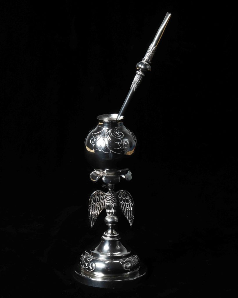 (Mate de&nbsp;Tapita, Bombilla de Plata)&nbsp;
Silver&nbsp;Mate&nbsp;cup and dried gourd with silver straws, circa 1990s&nbsp;
U.S. Embassy Buenos Aires, Argentina&nbsp;


Mate&nbsp;(rhymes with ‘okay’) in Argentina is a traditional, caffeinated herbal infusion made from dried&nbsp;yerba mate&nbsp;leaves and served communally from a shared gourd (the&nbsp;mate) with a&nbsp;bombilla, or metal straw.&nbsp;&nbsp;

The ritual of drinking and sharing tea made from hot water and&nbsp;yerba&nbsp;buena&nbsp;leaves is thousands of years old. It symbolizes friendship, hospitality and national identity and is enjoyed daily by people of all&nbsp;walks of life&nbsp;for energy and social connection. Typically, one person, (the&nbsp;cebador) prepares the&nbsp;mate&nbsp;and passes it around.&nbsp;
The silver&nbsp;mate&nbsp;features an intricately crafted eagle at its base, adding symbolic strength and elegance to its design. The couple’s&nbsp;mate&nbsp;with two&nbsp;bombillas&nbsp;is made from a dried and polished gourd, with decorative silver finishings. A couple’s&nbsp;mate&nbsp;is often given to newlyweds.&nbsp;&nbsp;&nbsp;

No record exists of the provenance of these items, but they were&nbsp;likely a&nbsp;gift, as are many items in the heritage collections of U.S. diplomatic and consular missions.&nbsp;
